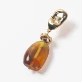 Caravanas colgantes con base metálica dorada de forma irregular y dije de piedra ámbar en tono marrón translúcido.