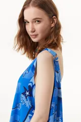 Vestido largo azul con estampado de estrellas de mar y flores. Tiene breteles finos regulables, cuello redondo y espalda descubierta.