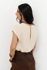 Blusa rosada de lino satinado con cuello redondo y mangas cortas. Presenta una costura vertical en el centro del frente.