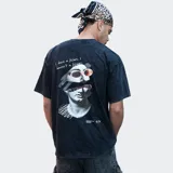 Remera oversize color negro con efecto acid wash y diseño gráfico en la espalda que combina una escultura clásica con gafas de sol y texto.