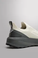 Zapatillas deportivas sin cordones para hombre, color blanco hueso con suela gris. Fabricadas en tejido de punto transpirable con puntera y talón reforzados con material Shield Protect Max. Cuentan con tirador trasero, plantilla OrthoLite® extraíble y entresuela Spume Foam V3.