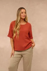 Blusa de manga corta color terracota, con cuello redondo, corte recto holgado y un bolsillo aplicado en el pecho.