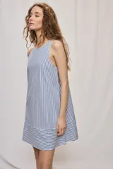 Vestido corto sin mangas con escote redondo y diseño evasé a rayas verticales celestes y blancas, con detalle de rayas horizontales en el ruedo.