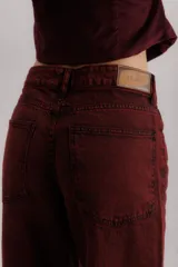 Pantalón de jean color bordó, corte baggy, tiro medio, con cuatro bolsillos y pinzas en las rodillas.