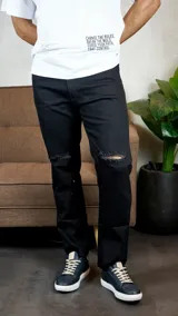 Jean de corte recto y color negro, con roturas desgastadas a la altura de las rodillas.