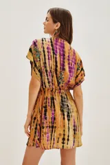 Vestido corto de estilo kimono con estampado tie-dye en tonos mostaza, violeta y negro. Presenta escote en V profundo, mangas cortas amplias y ajuste en la cintura con cordón. Incluye detalles de bordados decorativos con cuentas en el escote y la falda.