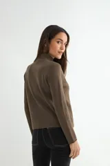Polera negra de tejido de punto acanalado, con cuello alto y mangas largas.