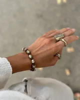 Pulsera artesanal compuesta por una serie de cuentas metálicas irregulares ensartadas en un hilo de algodón natural. Diseño rústico y minimalista.