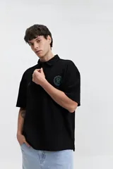 Remera polo color crema con logo bordado en el pecho, de corte amplio y mangas cortas.