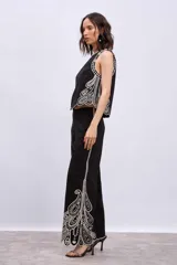 Blusa negra sin mangas, de corte recto y escote redondo, con detalles de bordados contrastantes en color blanco en los bordes y costados.