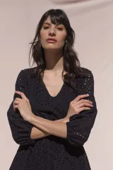 Vestido corto negro de broderie de algodón, con escote en V, mangas tres cuartos, cintura elastizada, falda corte A con volado y forro interior.