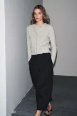 Chaqueta de lana 100% color gris claro, con cuello redondo, manga larga y cierre frontal con botones.