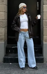 Pantalón de jean estilo wide leg, tiro bajo, con diseño de cinco bolsillos y cierre frontal con botón y cremallera. Presenta un lavado claro y corte holgado en las piernas.