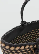 Bolso tipo tote confeccionado con un diseño trenzado en colores negro y beige. Cuenta con doble asa de mano trenzada y detalles metálicos dorados.