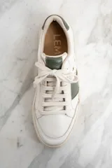 Zapatillas urbanas de cuero color blanco con detalles en verde.