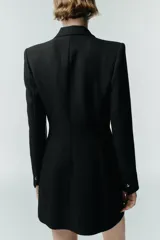 Blazer larga negra con cuello solapa, manga larga y bolsillos de vivo en el delantero. Cierre frontal con dos botones plateados.