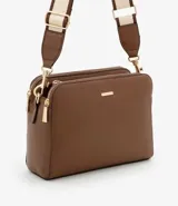 Bolso bandolera de tamaño mediano confeccionado en poliuretano color marrón. Presenta tres compartimentos independientes con cierre de cremallera, herrajes metálicos dorados y una correa de hombro ajustable de cinta tejida bicolor.