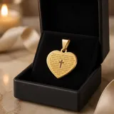 Dije en forma de corazón de acero dorado, con una cruz central y la oración del Padre Nuestro grabada en su superficie.