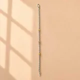 Pulsera de cadena de eslabones entrelazados en plata 925, con tres apliques cilíndricos texturizados en oro. Cierre de mosquetón.