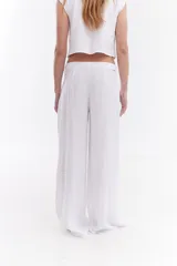 Pantalón sastrero de lino italiano color beige, de corte recto y holgado, con aberturas laterales en la cintura y pinzas.