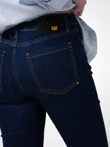 Jeans de corte ajustado y tiro medio en color azul oscuro. Presenta diseño clásico de cinco bolsillos, cierre frontal con cremallera y botón, y detalles de marca en los remaches y la pretina.
