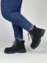 Borcego negro de caña baja con suela track y cordones combinados en blanco y negro.