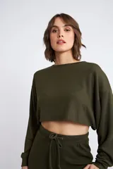 Buzo corto de tejido rib en color verde militar, con mangas largas y cuello redondo. Presenta un diseño holgado y cropped.