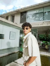 Camisa de manga corta color crudo, confeccionada en gabardina, con cuello camisero y botones frontales. Presenta un bolsillo de parche en el pecho y bordado en la espalda.