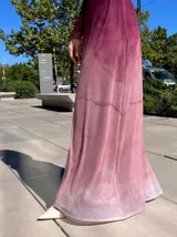 Vestido largo de manga larga con efecto degradado que va desde un tono fucsia oscuro en la parte superior hasta un rosa claro en el ruedo. Presenta un corte ajustado y cuello redondo.