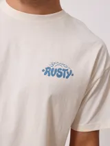 Remera de algodón color crema, corte oversize, con estampado frontal pequeño de la marca Rusty en azul.