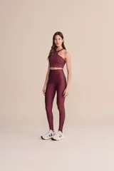 Top deportivo color bordó con corte asimétrico en el frente, diseño de impacto medio y relleno extraíble.