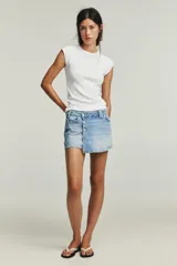 Falda pantalón de tiro alto confeccionada en denim, con diseño cruzado y cierre frontal mediante botones metálicos. Cuenta con cinco bolsillos y trabillas para cinturón.