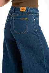 Pantalón jean de corte wide leg, tiro alto y color azul oscuro, con diseño clásico de cinco bolsillos y costuras en contraste.