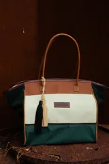 Bolso de fin de semana estilo tote de lona con estampado camuflado, detalles en cuero marrón y gamuza azul, manijas largas y borla decorativa colgante.
