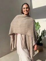 Ruana tejida en punto jersey, color negro con destellos brillantes de lurex. Presenta una etiqueta de cuero sintético con logo en la parte posterior.