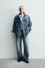 Parka de denim de algodón con efecto lavado, de color azul medio. Presenta cuello solapa, manga larga con puño abotonado, cierre frontal de botonadura oculta y cintura ajustable con cordón interior. Posee cuatro bolsillos utility de plastrón con solapa: dos en el pecho y dos en la cadera.