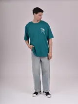 Remera color verde petroleo, de manga corta y corte oversize, con estampa en el pecho izquierdo que dice 'Noble Origins' junto a un diseño floral.