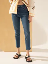 Jeans slim de tiro medio color azul, con largo al tobillo y parches bordados de labios rojos en el bolsillo delantero.