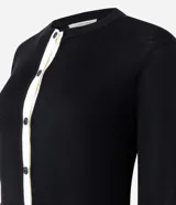 Cardigan de punto Marfinno, color negro con detalles en blanco en la botonera y el ruedo. Presenta cuello redondo, mangas largas y cierre frontal con botones oscuros.