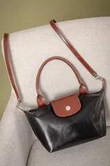 Cartera pequeña de mano tipo tote, confeccionada en gamuza color azul, con solapa y asas en cuero sintético con textura de reptil. Incluye cierre superior y correa larga ajustable y extraíble.