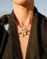 Collar tipo gargantilla con dije de flor metálica de acabado brillante, suspendido de un cordón doble de seda natural teñido a mano en color rojo.