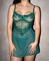 Babydoll de encaje verde oscuro con transparencias, tirantes finos y detalle de moño en el centro del escote. Incluye bata a juego con mangas anchas de encaje y tanga hilo.