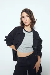 Remera cropped blanca de manga corta, con cuello redondo y terminaciones en contraste de color marrón en cuello y mangas. Inspirada en los clásicos de los años 80.