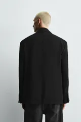 Blazer de corte relajado confeccionada en tejido fluido con mezcla de viscosa. Presenta cuello con solapas de muesca, manga larga con puños abotonados, bolsillos de solapa en la cadera y cierre frontal con botones.