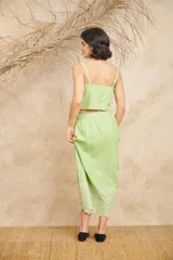 Conjunto de dos piezas compuesto por un crop top de breteles anchos y una pollera midi, ambos en color azul con detalles de bordado floral blanco en el ruedo y el lateral del top.