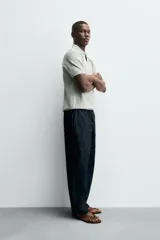 Jersey de punto color verde oliva, de calce relajado (relaxed fit), con cuello solapa y abertura frontal en forma de V. Es de manga corta y presenta acabados en rib en puños y ruedo.