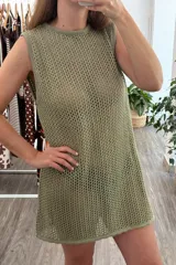 Vestido sin mangas, color verde oliva, tejido a crochet con patrón de rombos o calado abierto. Tiene cuello redondo y corte recto que cae hasta medio muslo.
