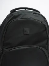 Mochila negra con tres compartimentos con cierre y dos bolsillos laterales abiertos con elástico.