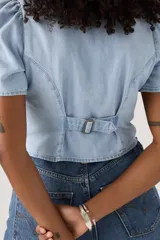 Camisa de jean celeste con botones, mangas cortas abullonadas y cuello en V.