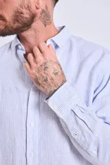 Camisa de corte regular con diseño de rayas verticales finas en tonos claros, cuello clásico y mangas largas con puños abotonados.